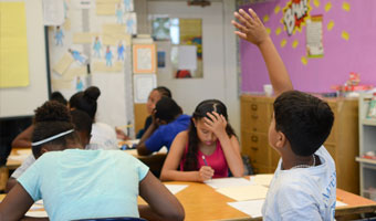 boy raises hand in classroom